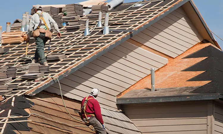 Full roof replacement in progress with workers removing old shingles