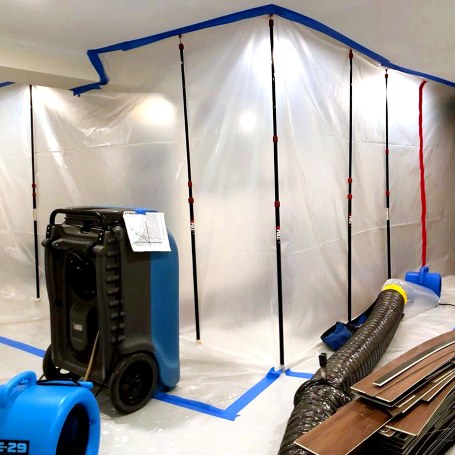 Technician setting up containment barriers and drying equipment in a water-damaged area