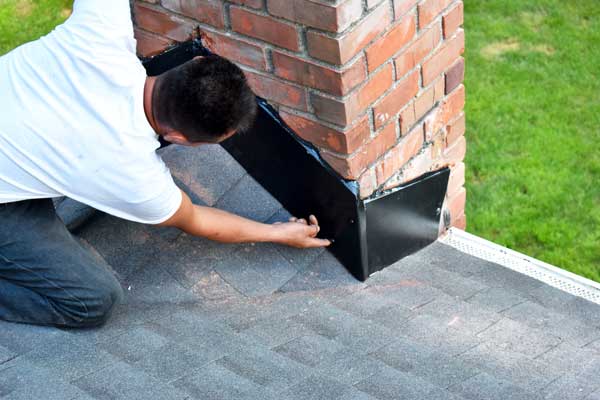 Technician sealing damaged flashing around a roof vent