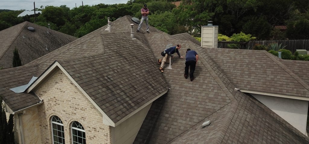 Roofer inspecting lifted shingles after a recent storm in McKinney