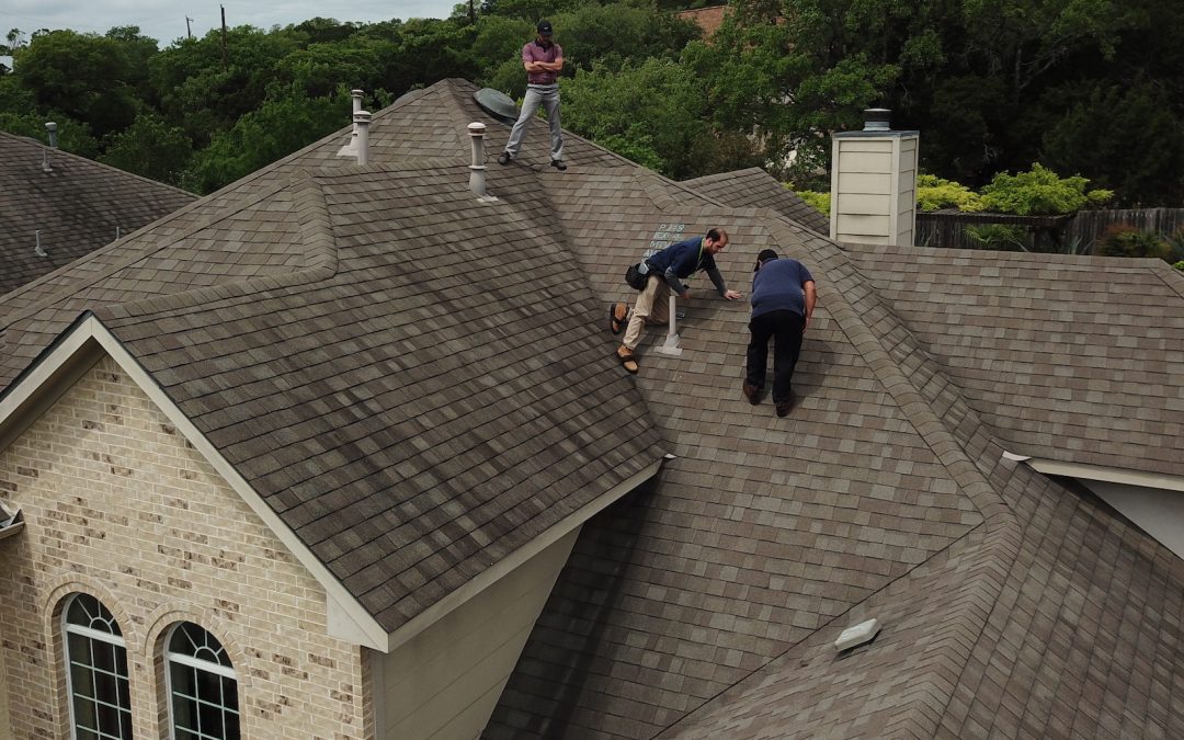 Roofer inspecting lifted shingles after a recent storm in McKinney