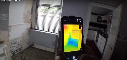 restoration technician using infrared camera to find moisture behind walls