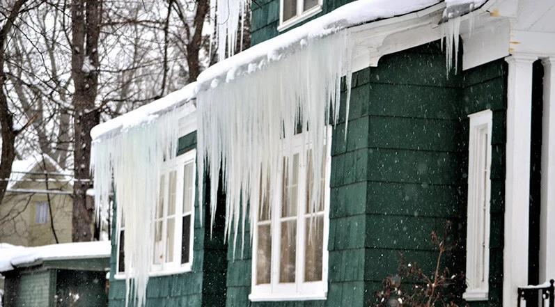 Ice accumulation and icicles on residential roofing in McKinney, TX after winter storm requiring roofing contractor inspection