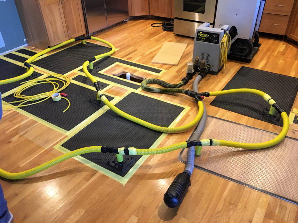Professional water damage restoration equipment including air movers and dehumidifiers set up in a Texas home interior