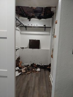 Closet with damaged ceiling materials, debris on the floor, and exposed wall sections.