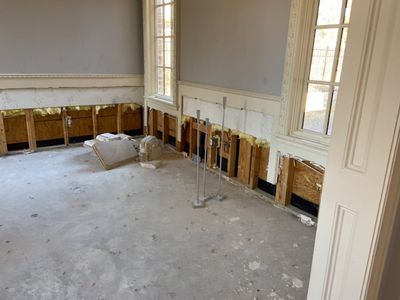 A large interior room with lower wall sections removed, exposed studs, and a bare floor.