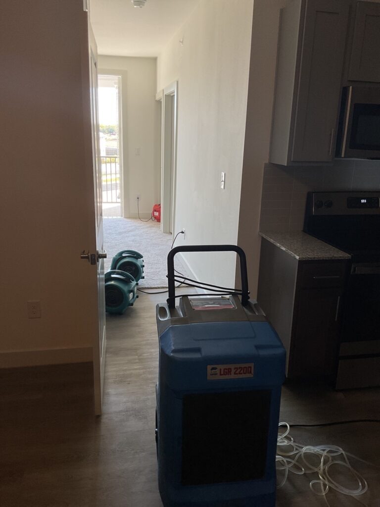 Dehumidifier and air movers set up in an apartment hallway for water mitigation drying in Waxahachie, TX