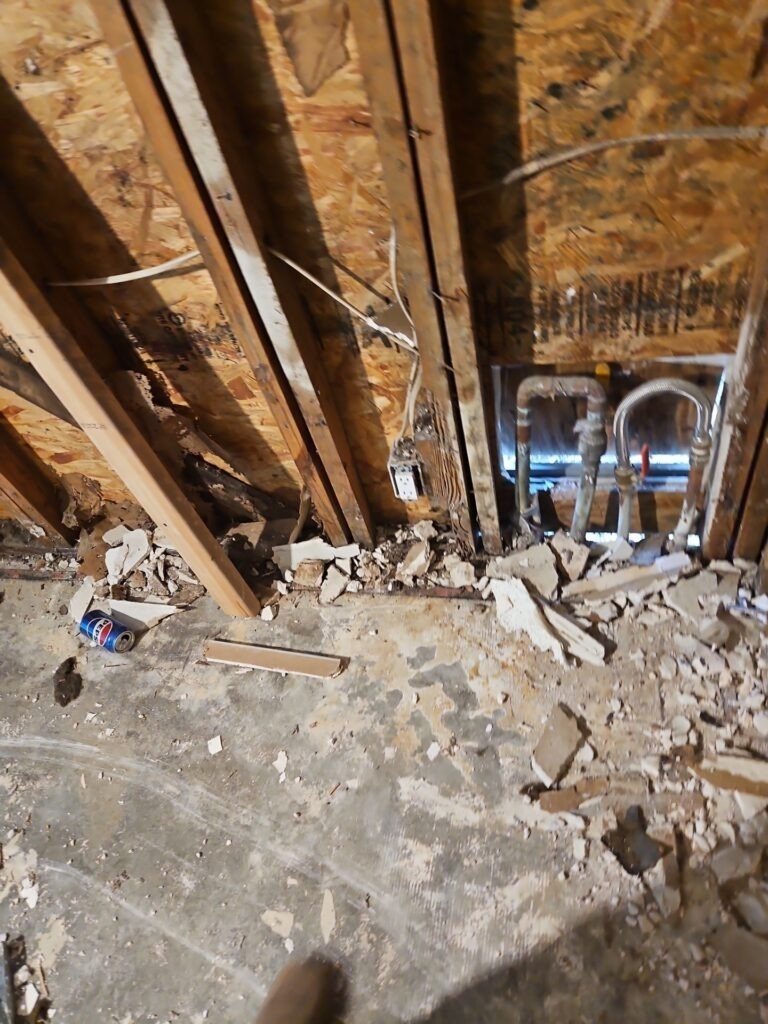 Attic in Dallas, TX showing demolition debris and exposed roof framing during water mitigation
