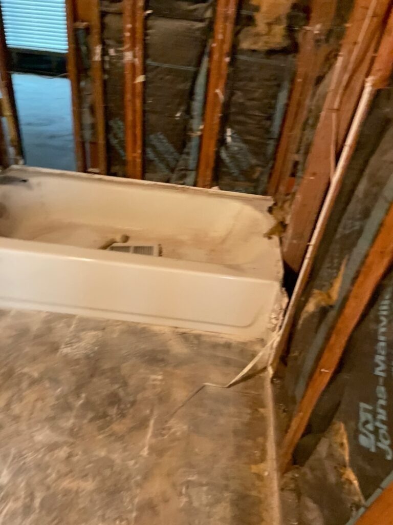Bathtub area with exposed wall studs and removed wall materials during water mitigation in Dallas, TX