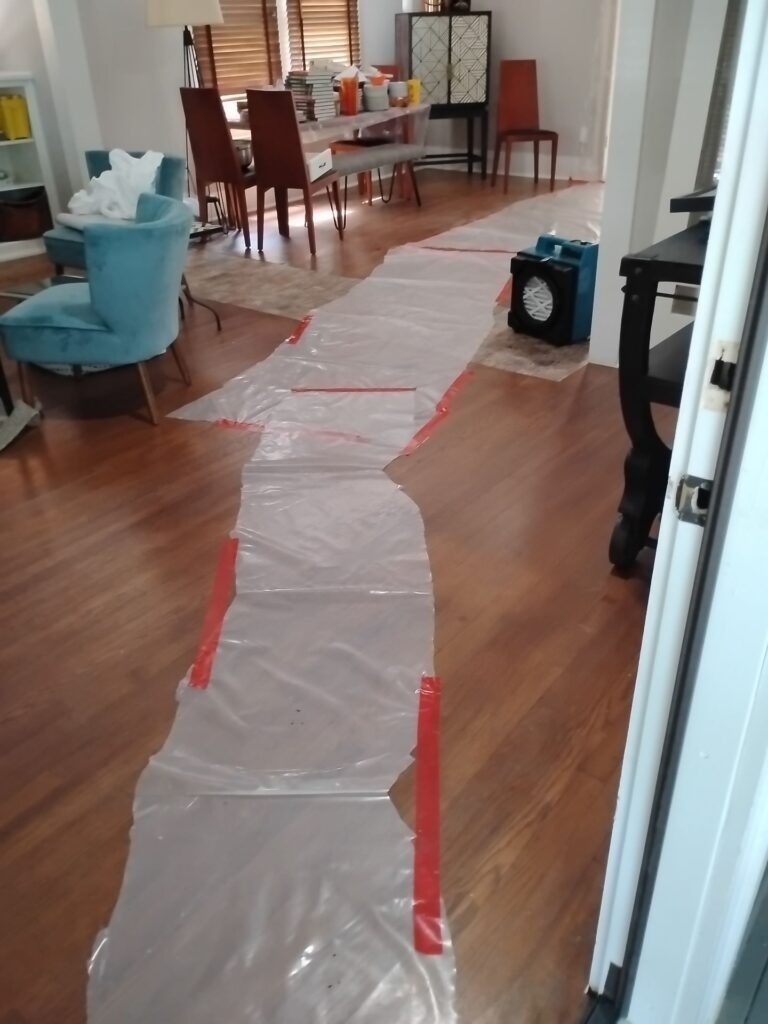 Protective plastic floor covering taped through a residential interior during mold remediation in Dallas, TX