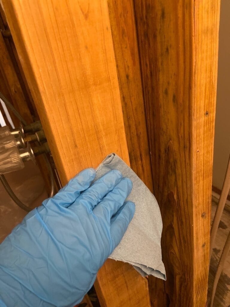 During: gloved hand collects a surface wipe sample from stained bathroom trim in The Colony, TX