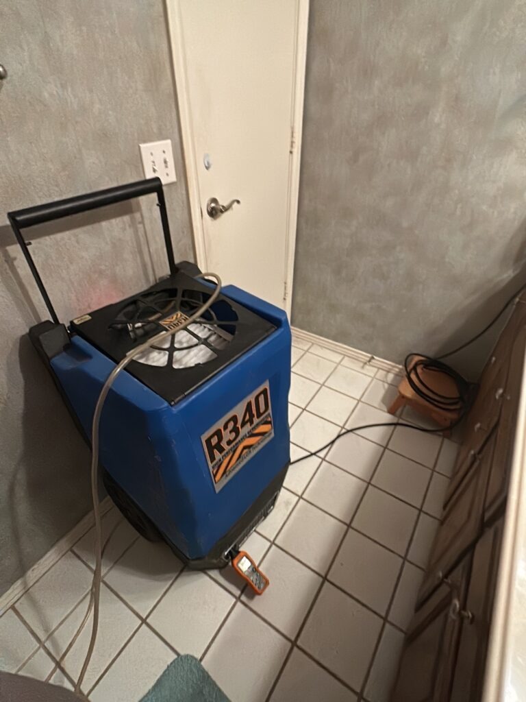 Dehumidifier set up on a bathroom tile floor during water mitigation in Plano, TX