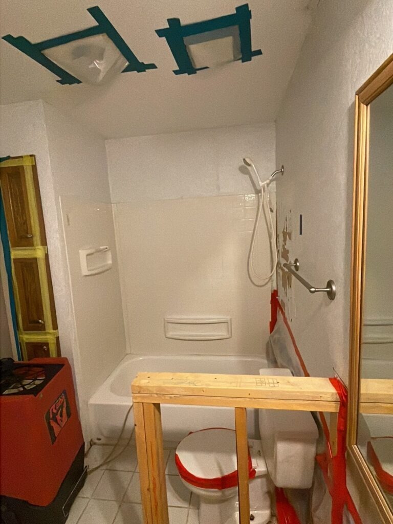 Bathroom in Plano, TX with ceiling openings, containment framing, and drying equipment during water mitigation