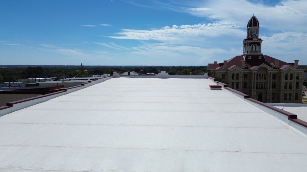 Aerial view of the completed white TPO membrane flat roof on a downtown commercial building in Bonham, TX