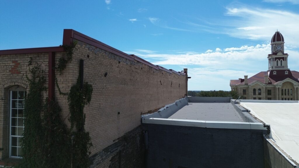 Aerial view of the finished white TPO membrane flat roof on a downtown commercial brick building in Bonham, TX