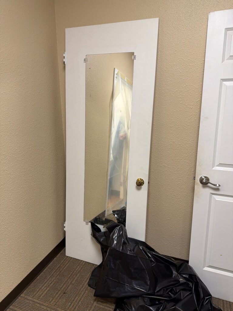 Black debris containment bag staged inside the controlled work area during commercial mold remediation in Commerce, TX