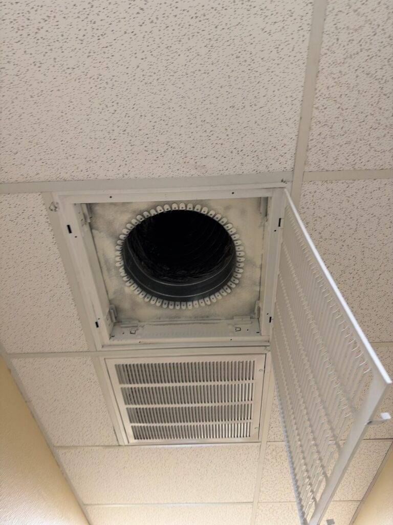 Open ceiling HVAC vent and adjacent return grille inspected during commercial mold remediation in Commerce, TX