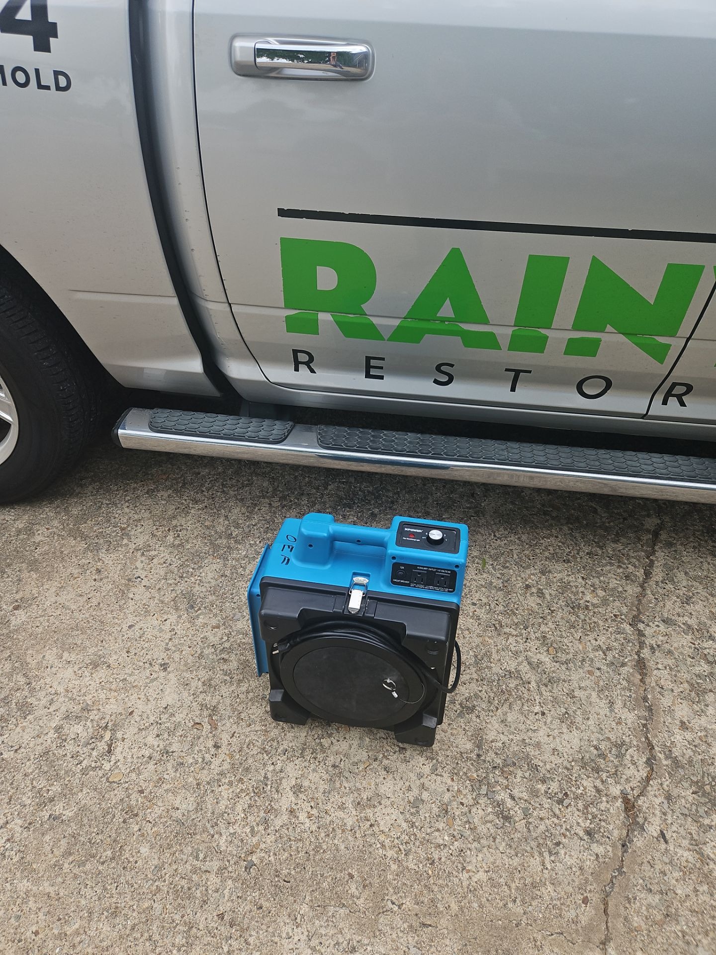 Portable air scrubber set up beside a Rainy Day restoration truck for commercial mold remediation in Commerce, TX