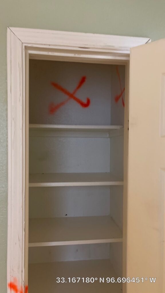 Open closet with shelving and spray paint markings documenting water mitigation demolition scope in McKinney, TX