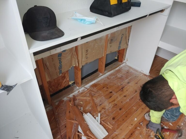 Worker removing damaged wall and baseboard materials in a bathroom during water mitigation in McKinney, TX