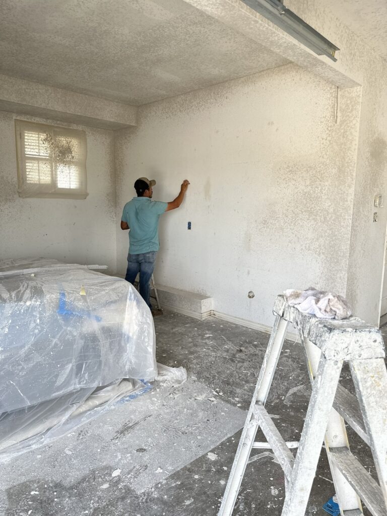 Worker applying finish to a repaired interior wall during water damage restoration in McKinney, TX