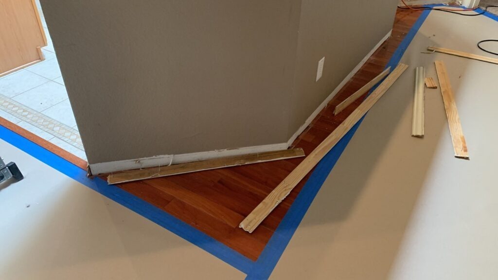 Protective floor covering taped over hardwood near a kitchen wall during water mitigation in Garland, TX