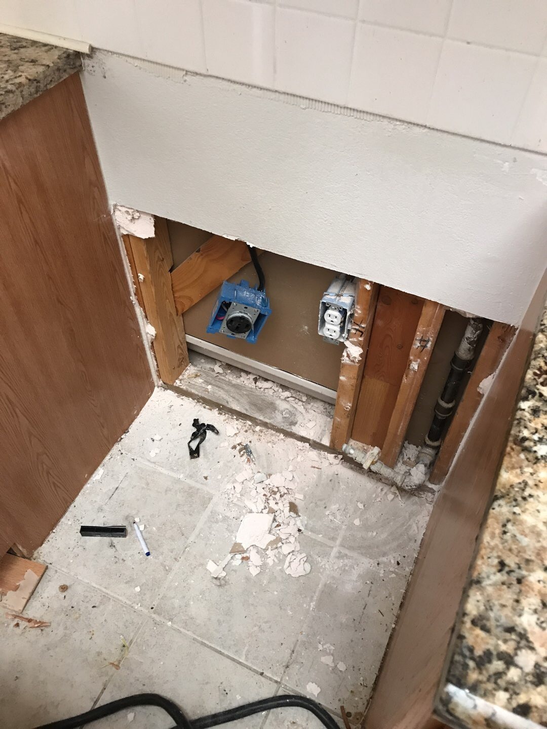 Cabinet opened to reach the wall — Garland TX Kitchen cabinet base with lower panel removed to expose the wall cavity during water mitigation in Garland, TX