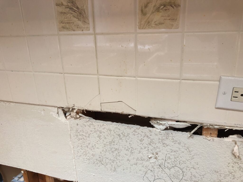 Kitchen tile backsplash opened along the wall during water mitigation in Garland, TX