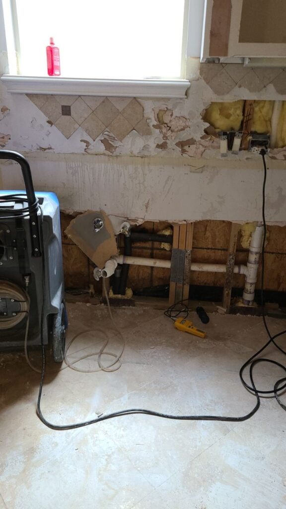 Kitchen wall opened with exposed framing and drying equipment during water mitigation in a McKinney, TX home