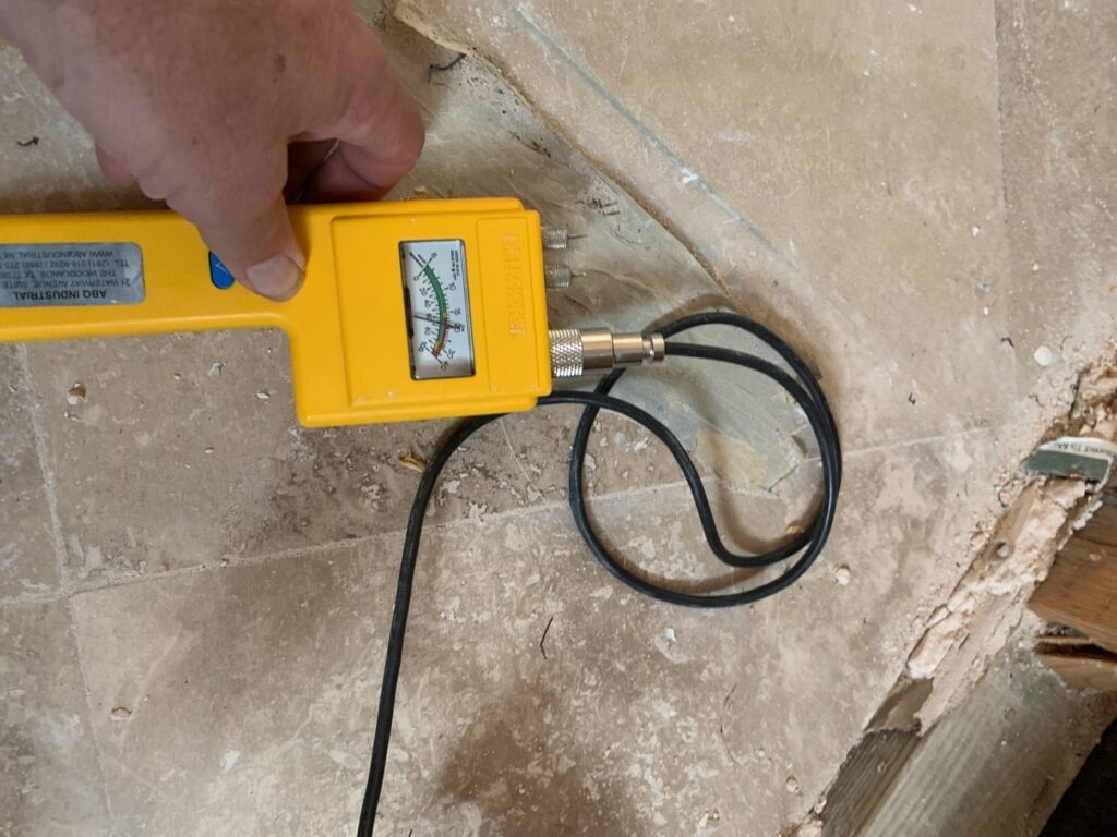 Technician using a moisture meter to check tile flooring during water mitigation in a McKinney, TX home