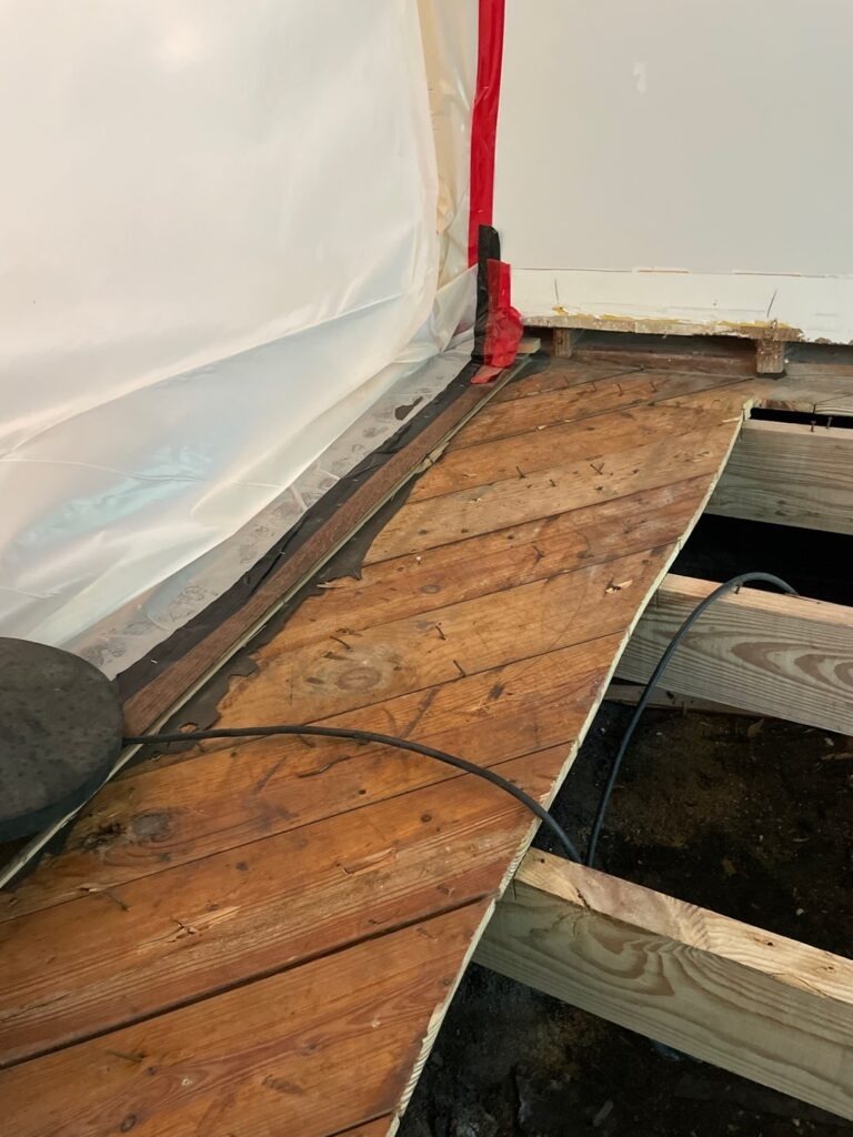 Containment sheeting installed beside exposed wood subfloor during mold remediation in a Dallas, TX residence