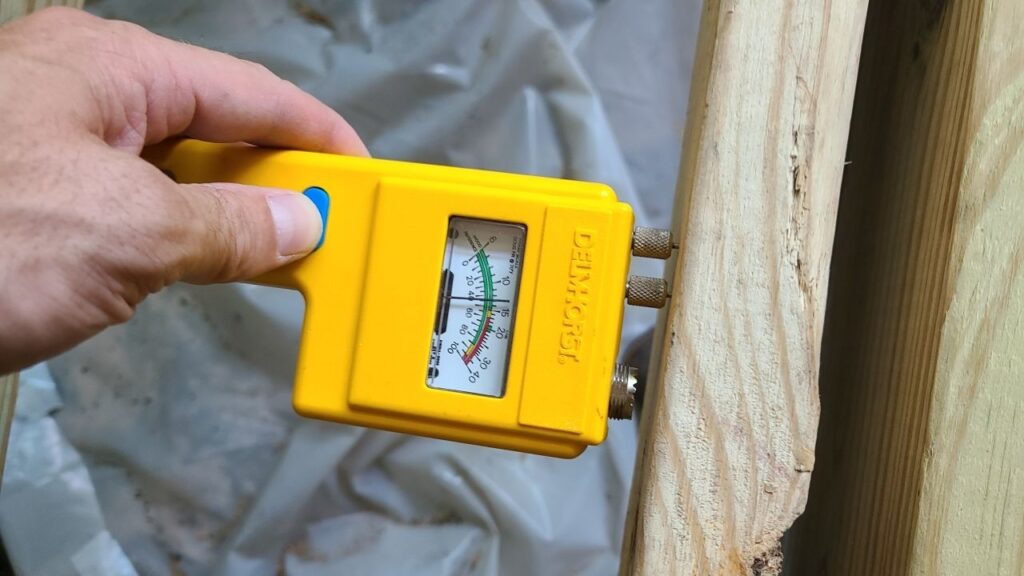 Moisture meter held against exposed wood framing during mold remediation in Dallas, TX