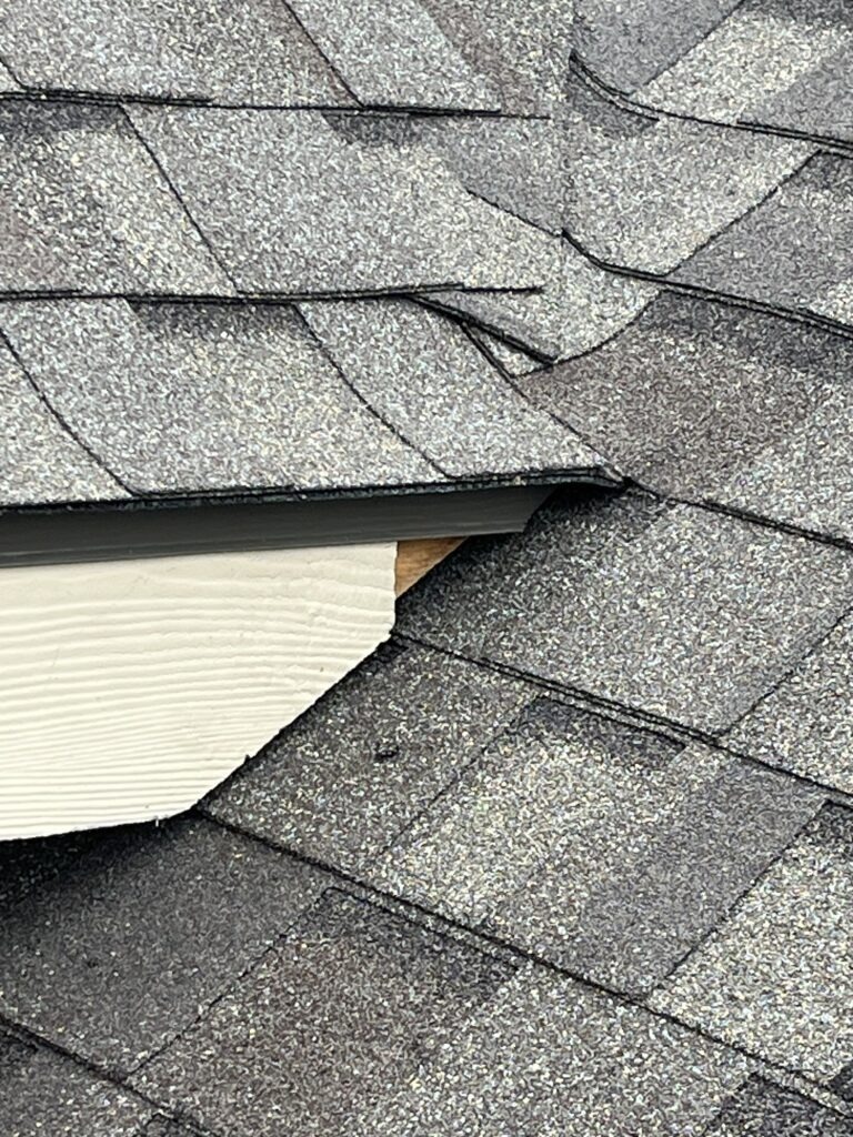 Close-up of lifted asphalt shingles exposing the roof edge on a residential home in Melissa, TX