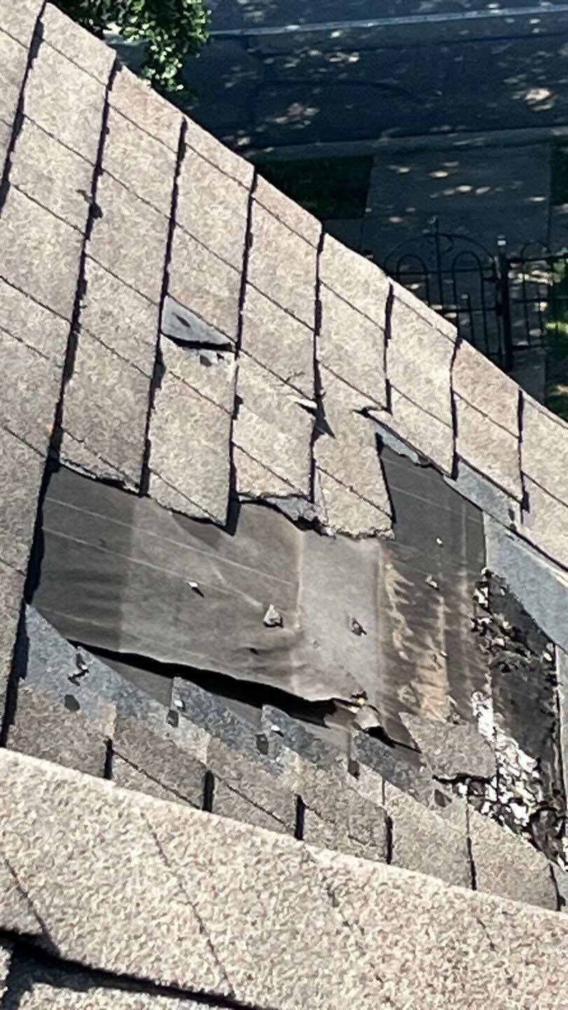 Damaged and missing roof shingles caused by tree impact