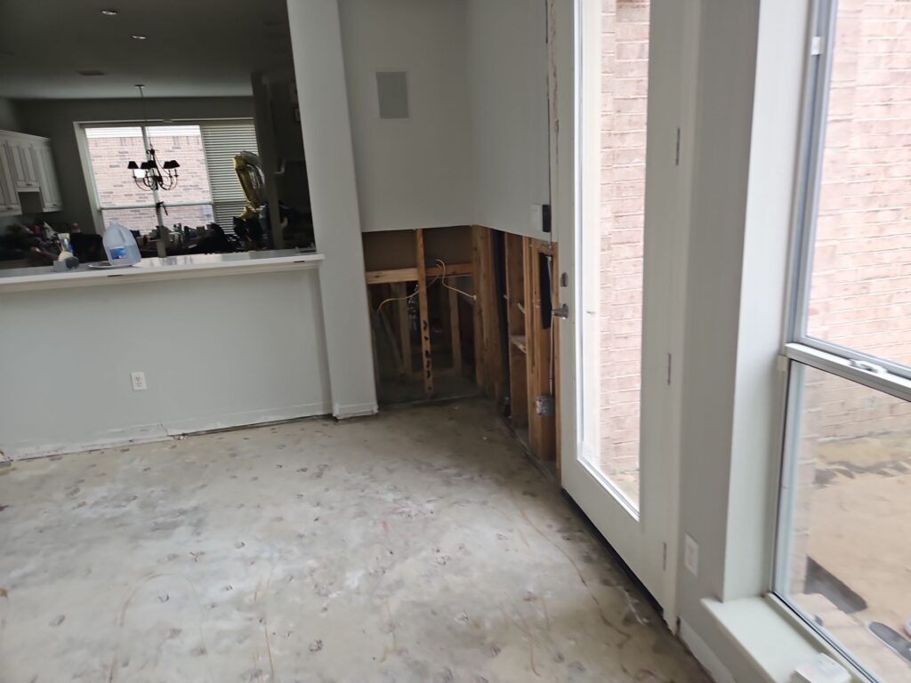 Interior room in an Allen, TX home showing partial wall demolition and removed flooring near tall windows