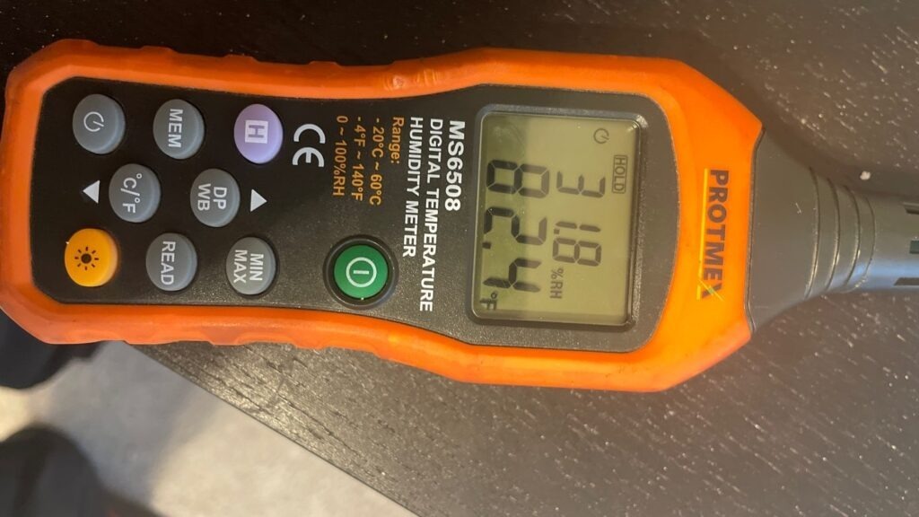 Moisture meter displaying an elevated reading during a water intrusion inspection in Van Alstyne, TX