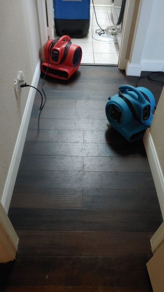 Air movers set up in a residential hallway to dry water-damaged flooring during mitigation in McKinney, TX
