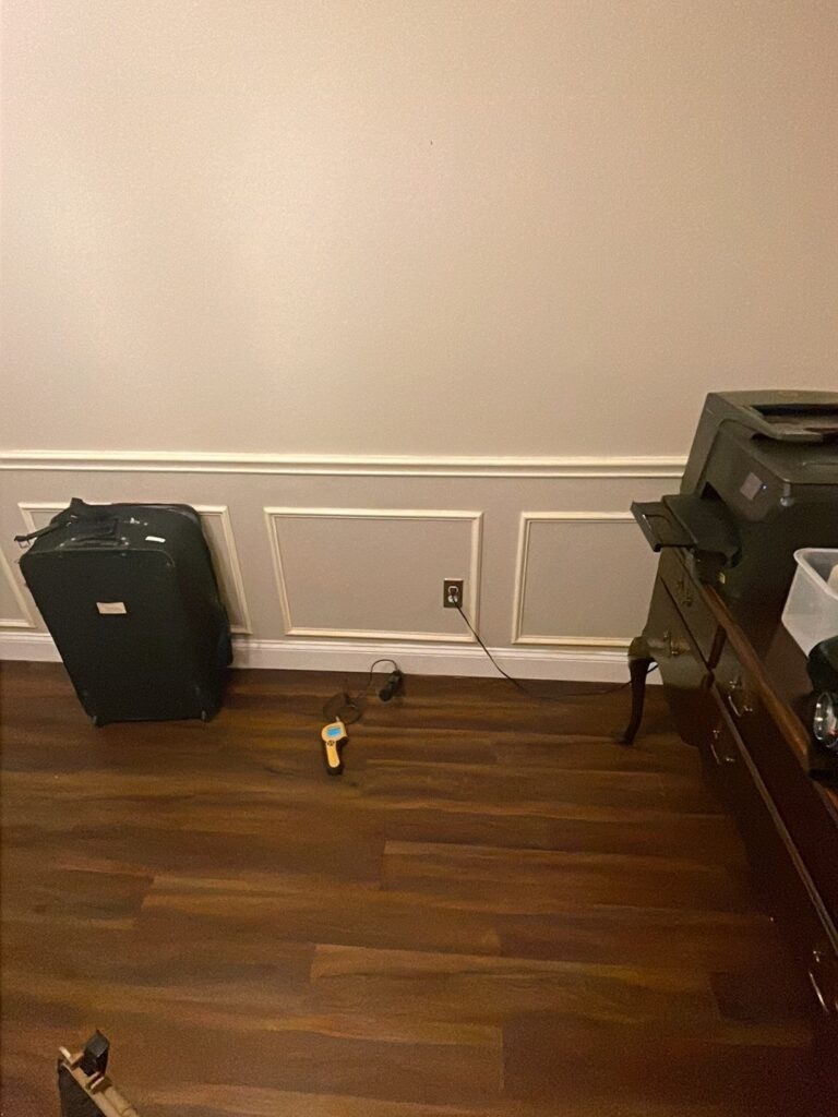 Air mover set against an interior wall to dry hardwood flooring during water mitigation in McKinney, TX