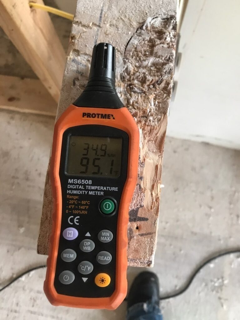 Moisture meter showing elevated readings on exposed interior wall framing during water mitigation in Dallas, TX