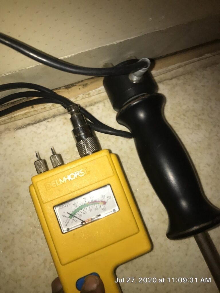 Moisture meter probe set up beneath flooring during water mitigation inspection in Denison, TX
