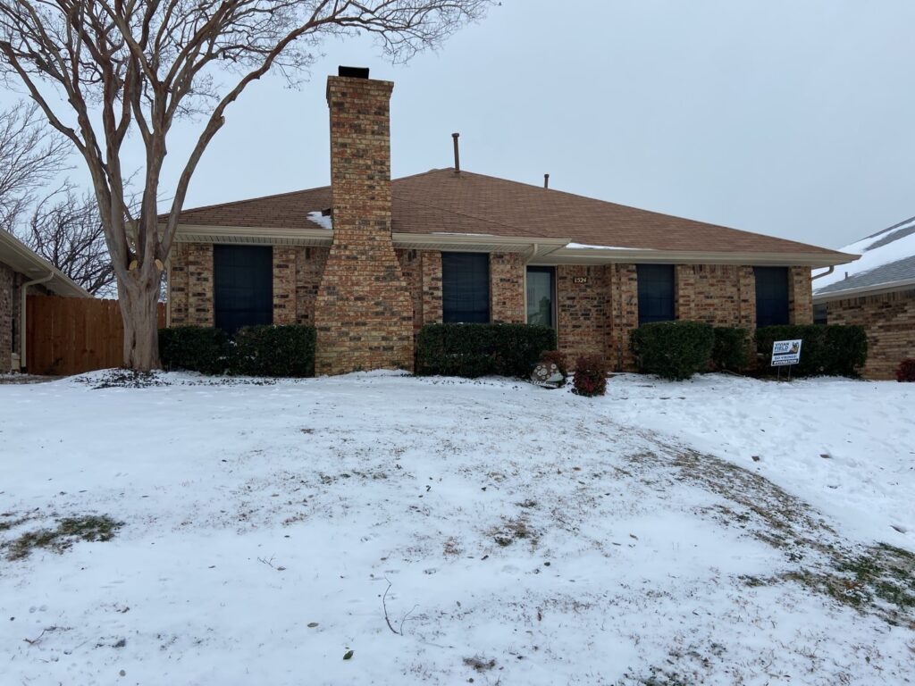 Snow-covered brick home in Carrollton, TX before winter water mitigation work
