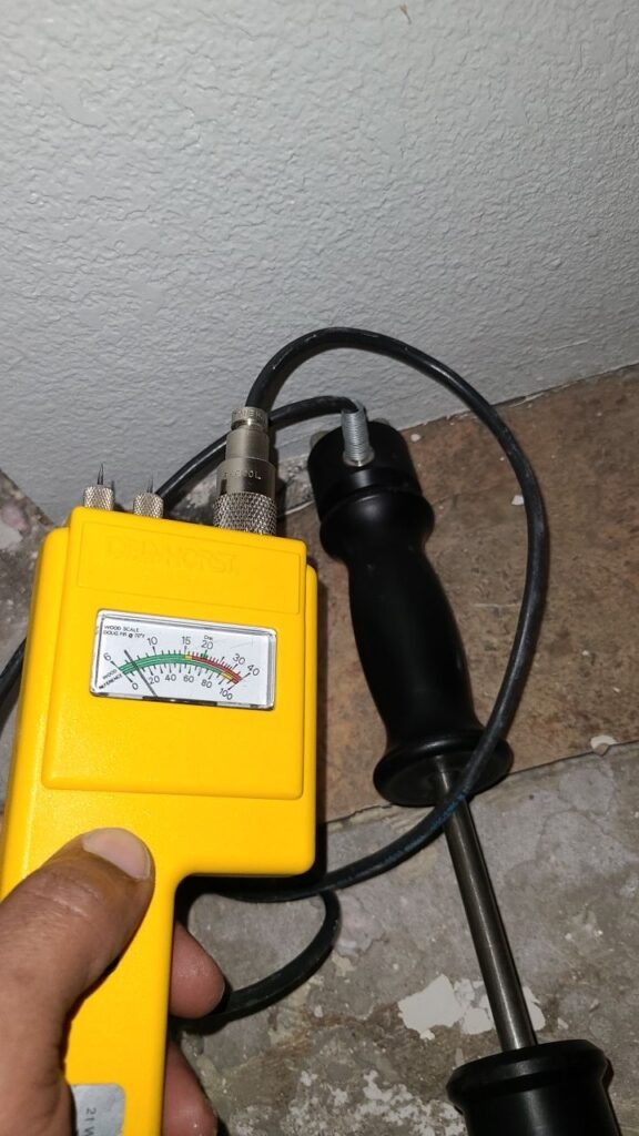 Technician taking moisture readings at a water-damaged interior wall in Carrollton, TX