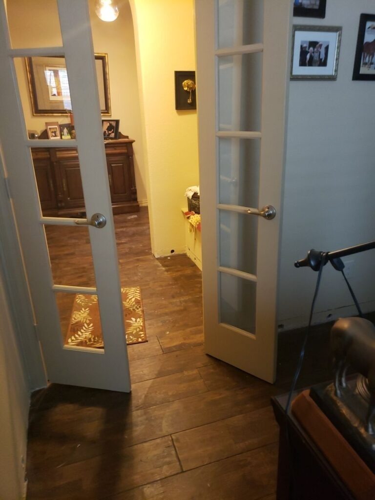 Residential interior in Denton, TX with affected flooring and drying equipment set up for water mitigation