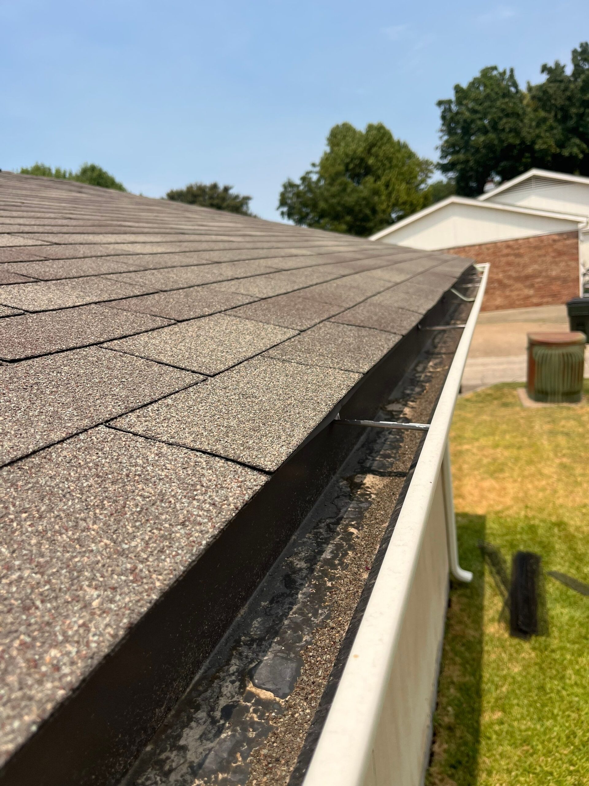 Before gutter cleaning in Plano, close-up shows the misdirected downspout found on site