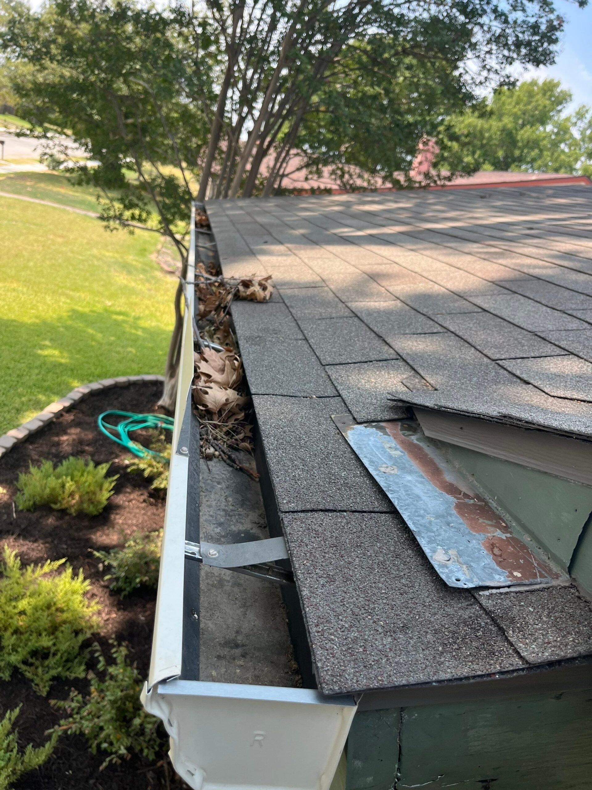 During gutter cleaning in Plano, crew member corrects the misdirected downspout on the home