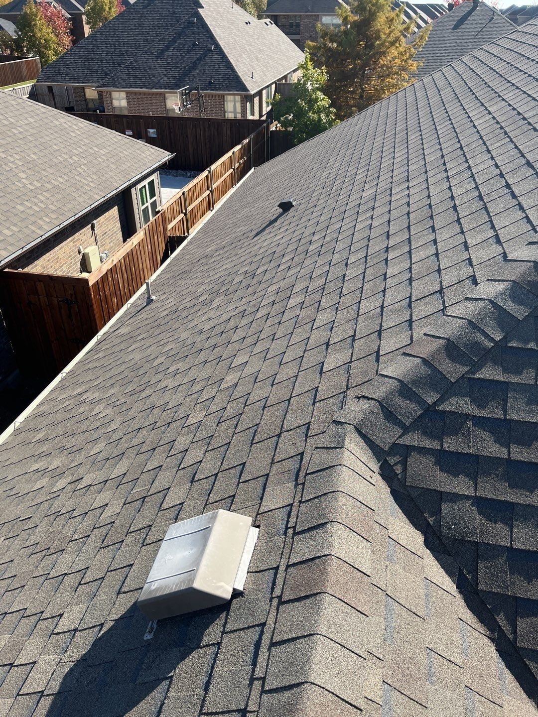 Wind-lifted shingles showing displaced edges before the roof replacement in Melissa, TX