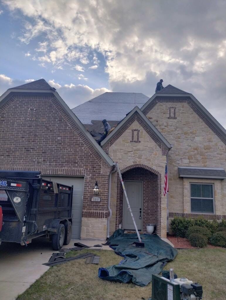 Crew tearing off damaged shingles during the roof replacement in Sherman, TX