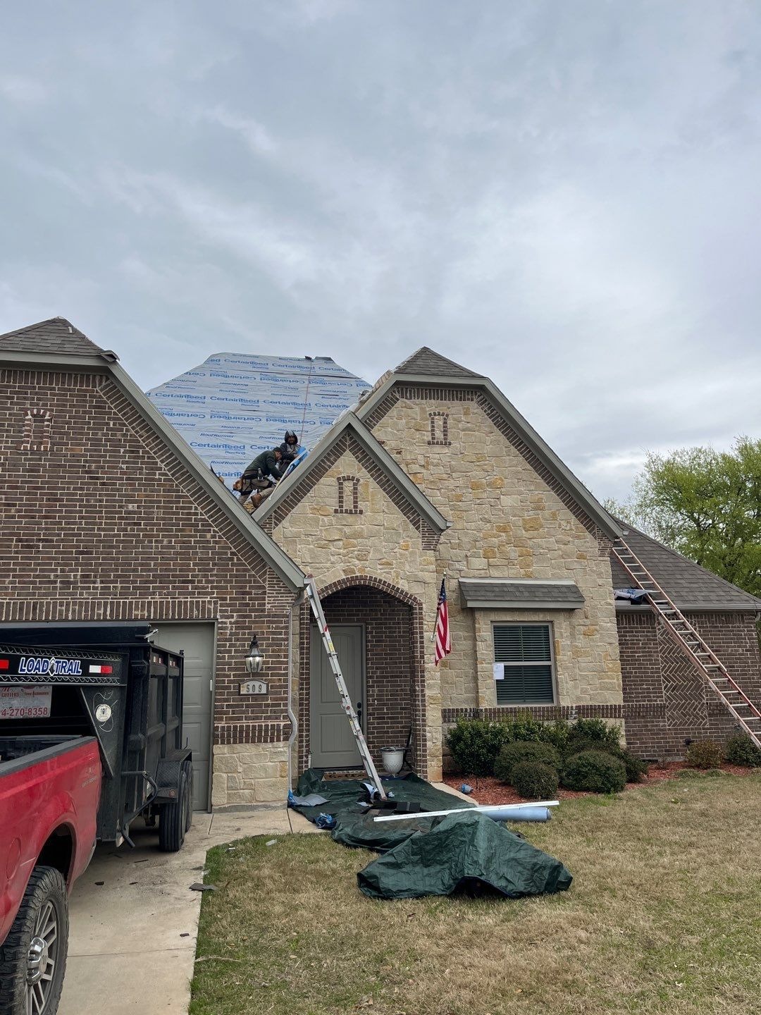 Crew installing new shingles on a steep slope during the roof replacement in Sherman, TX
