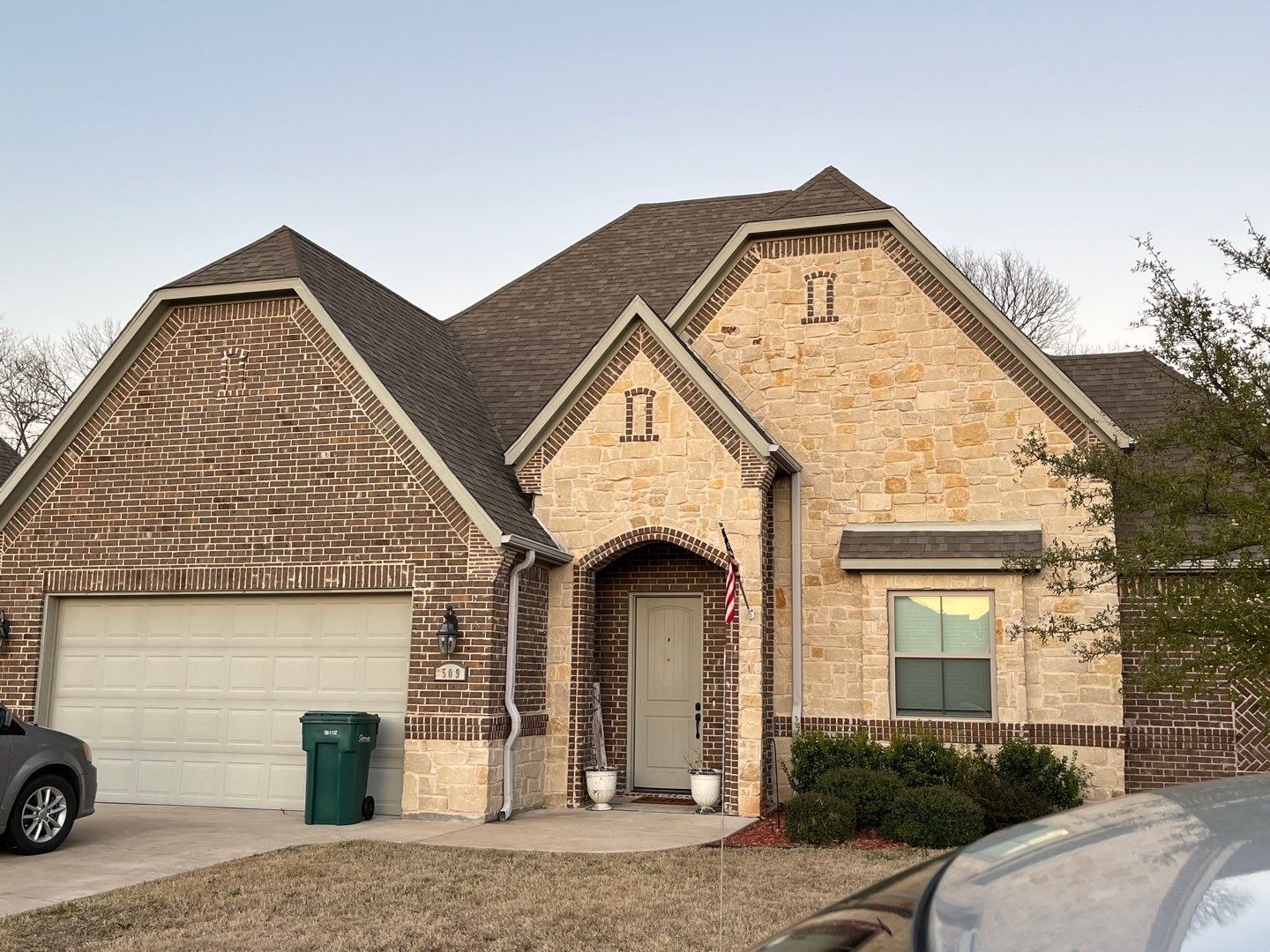 Hail-bruised shingles and wind-lifted edges before the roof replacement in Sherman, TX
