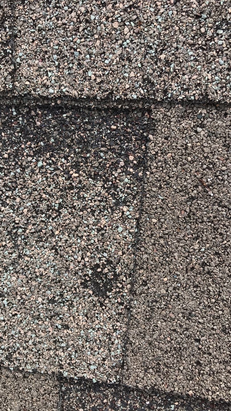Hail-cracked shingles across a roof slope before the roof replacement in Melissa, TX